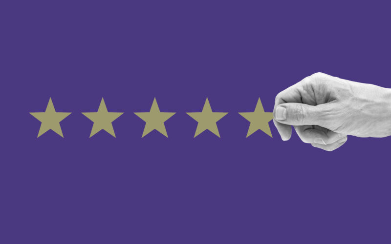 Cropped human hand arranging 5 stars against purple background.